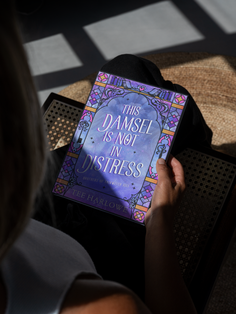 Person holding a book titled 'This Damsel is Not in Distress' with a decorative cover.