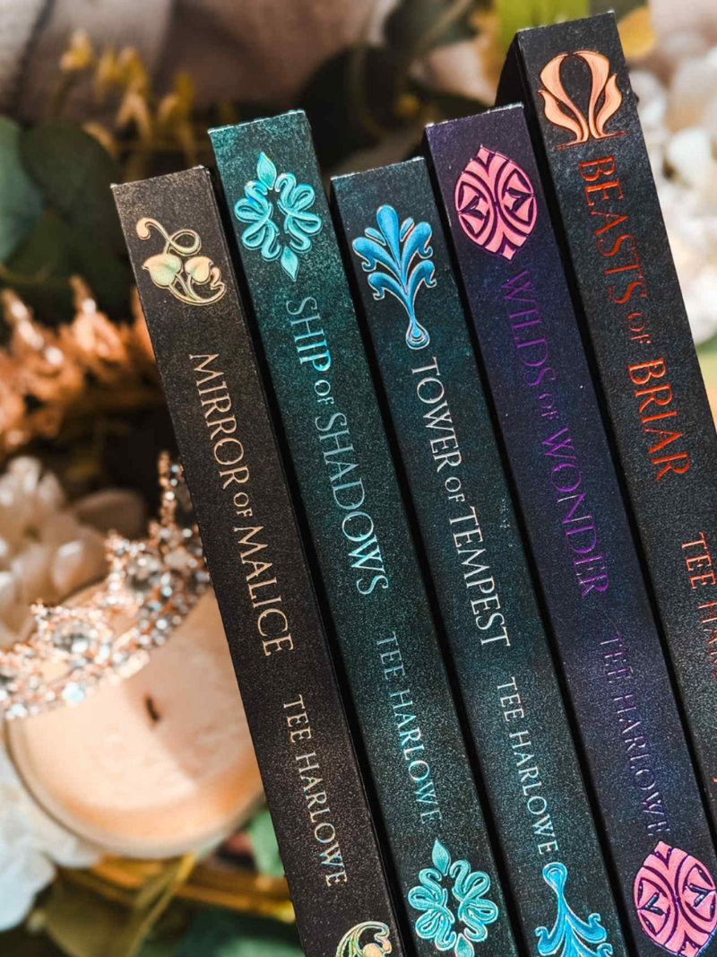 Row of book spines with decorative designs and titles on a blurred natural background