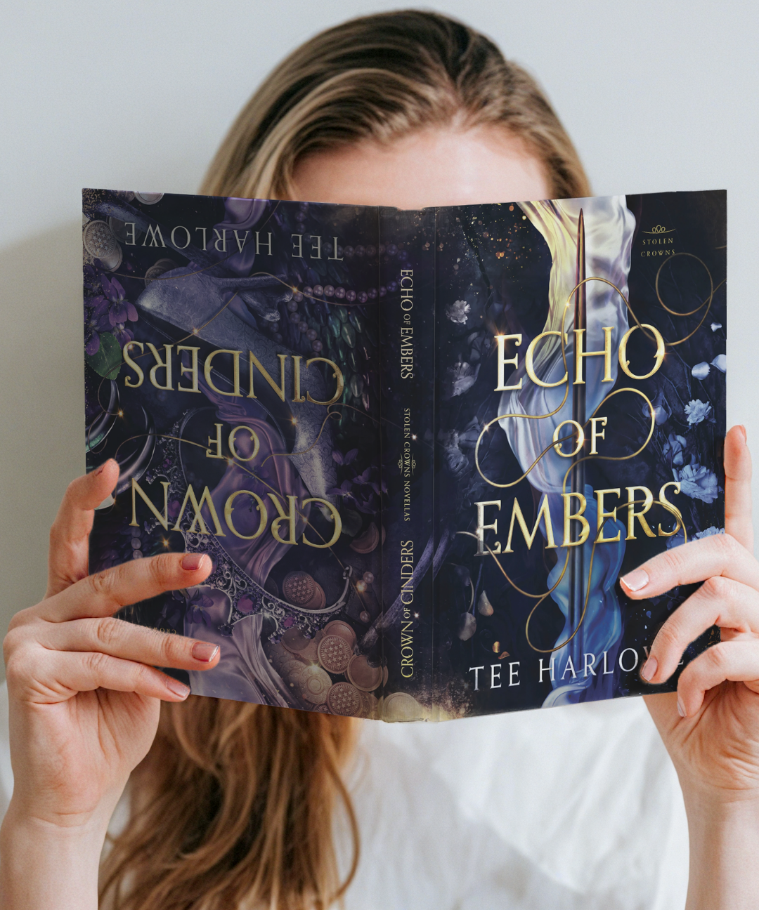 Person holding 'Echo of Embers' book by Tee Harlow in front of their face