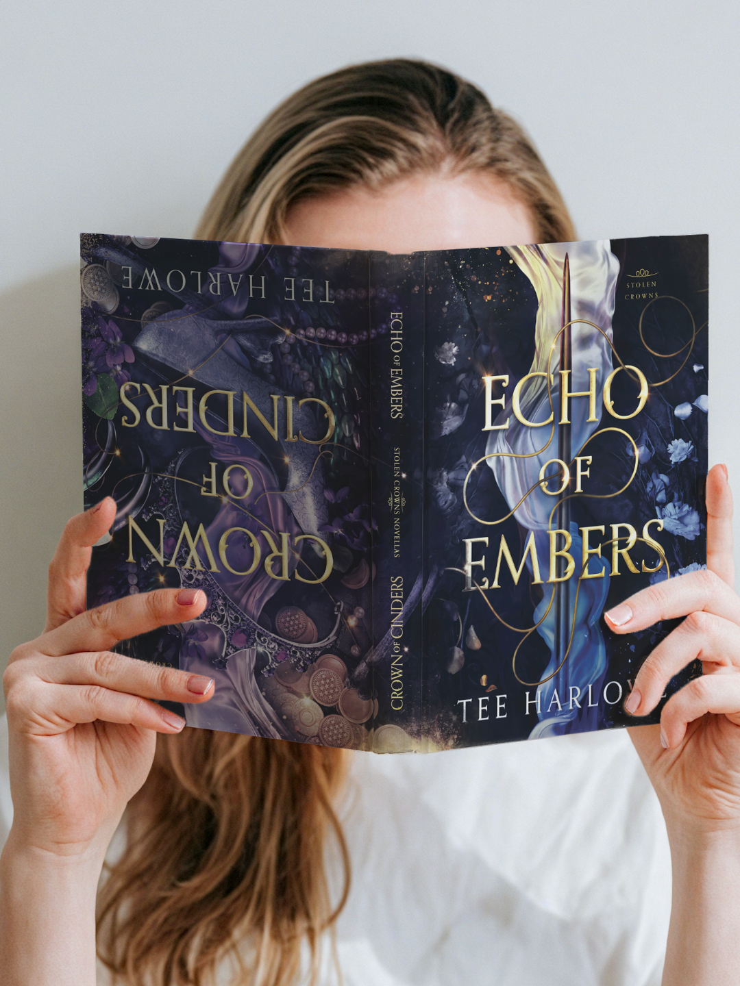 Person holding 'Echo of Embers' book by Tee Harlow in front of their face
