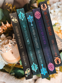 Row of book spines with decorative designs and titles on a blurred natural background