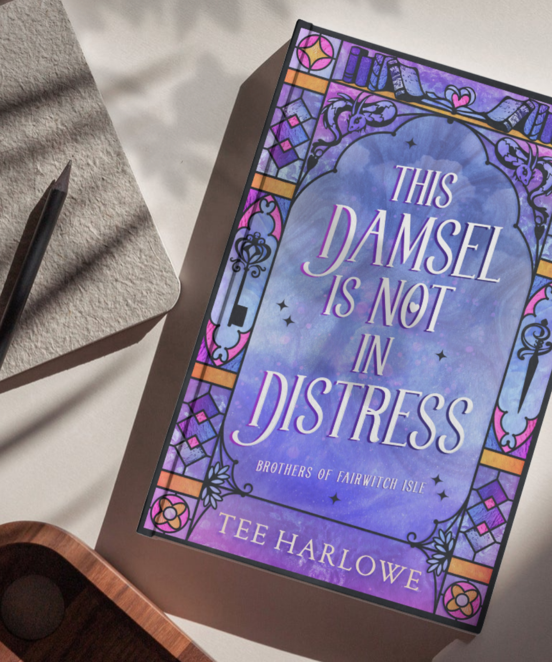 Book titled 'This Damsel is Not in Distress' by Tee Harlowe on a textured surface with a pen.