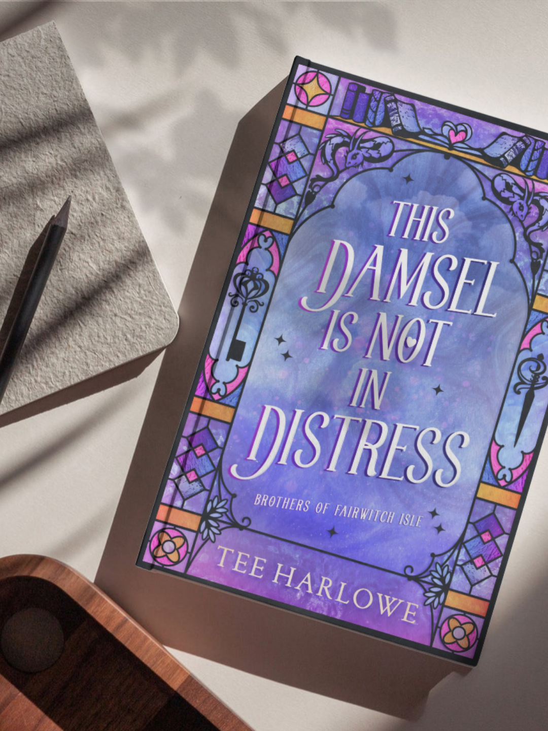 Book titled 'This Damsel is Not in Distress' by Tee Harlowe on a textured surface with a pen.